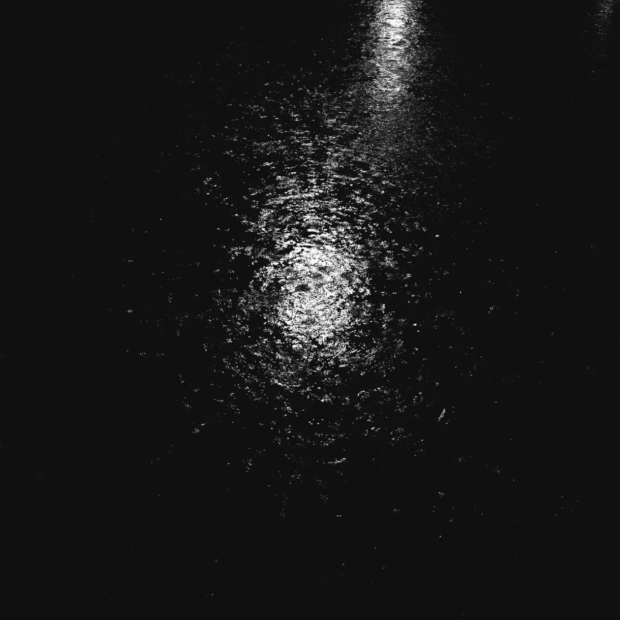 Un charco de baldeo atrapando la luz, de noche